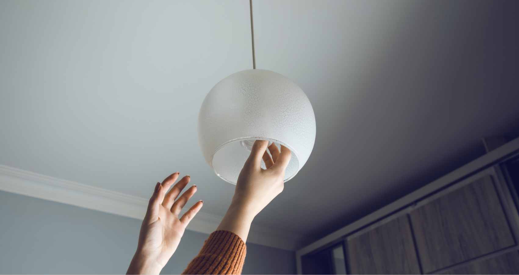 Persona colocando una nueva lampara en su casa